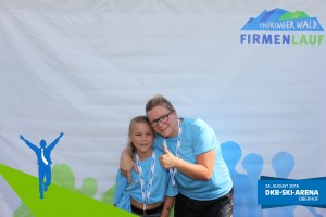 Teilnehmerin mit Kind vor der Fotowand beim Thüringer Wald Firmenlauf 2016 in der DKB-Ski-Arena Oberhof