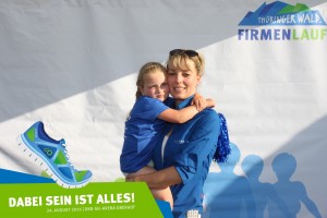 Teilnehmerin mit Kind vor der Fotowand beim Thüringer Wald Firmenlauf 2016 in der DKB-Ski-Arena Oberhof