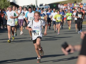teilnehmendes Kind beim Thüringer Wald Firmenlauf 2016 auf der Strecke, im Hintergrund viele ihm folgenden Läufer